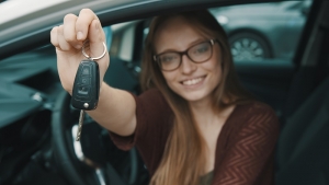 Young caucasian happy woman in front of the new car and holding keys